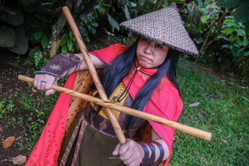 Pōhutukaryl Cosplay as Princess Raya, steely eyed, holding arnis sticks