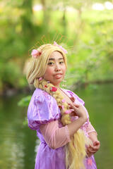 Pōhutukaryl Cosplay as Princess Rapunzel, touching her blonde braid