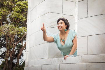 Pōhutukaryl Cosplay as Princess Jasmine, pointing excitedly out of a castle window