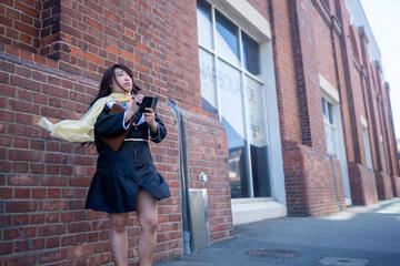 Pōhutukaryl Cosplay as Mia Fey, writing in a tiny notebook, scarf blowing in the wind