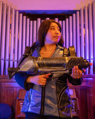 Pōhutukaryl Cosplay as Ashley Williams from Mass Effect 3, holding a gun and looking right in purple lighting